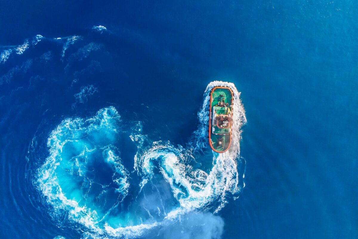 Tugboat blue sea port. Aerial top view.